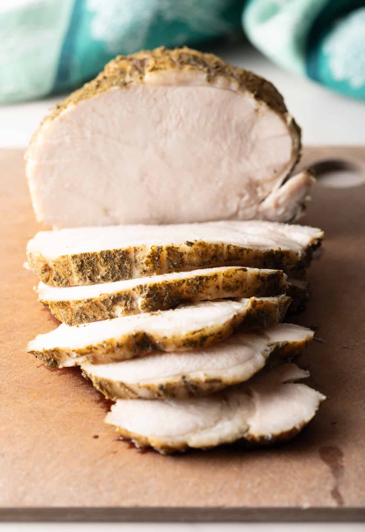 Sliced slow cooker turkey breast sitting on a cutting board.