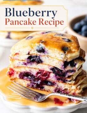 Single-image poster of a tall stack of fluffy blueberry pancakes drizzled with maple syrup and topped with fresh blueberries, styled in warm golden and deep red tones.