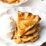 A slice of easy apple pie on a white plate, sitting next to a scoop of ice cream.