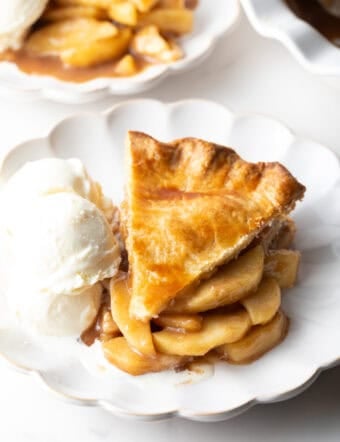 A slice of easy apple pie on a white plate, sitting next to a scoop of ice cream.